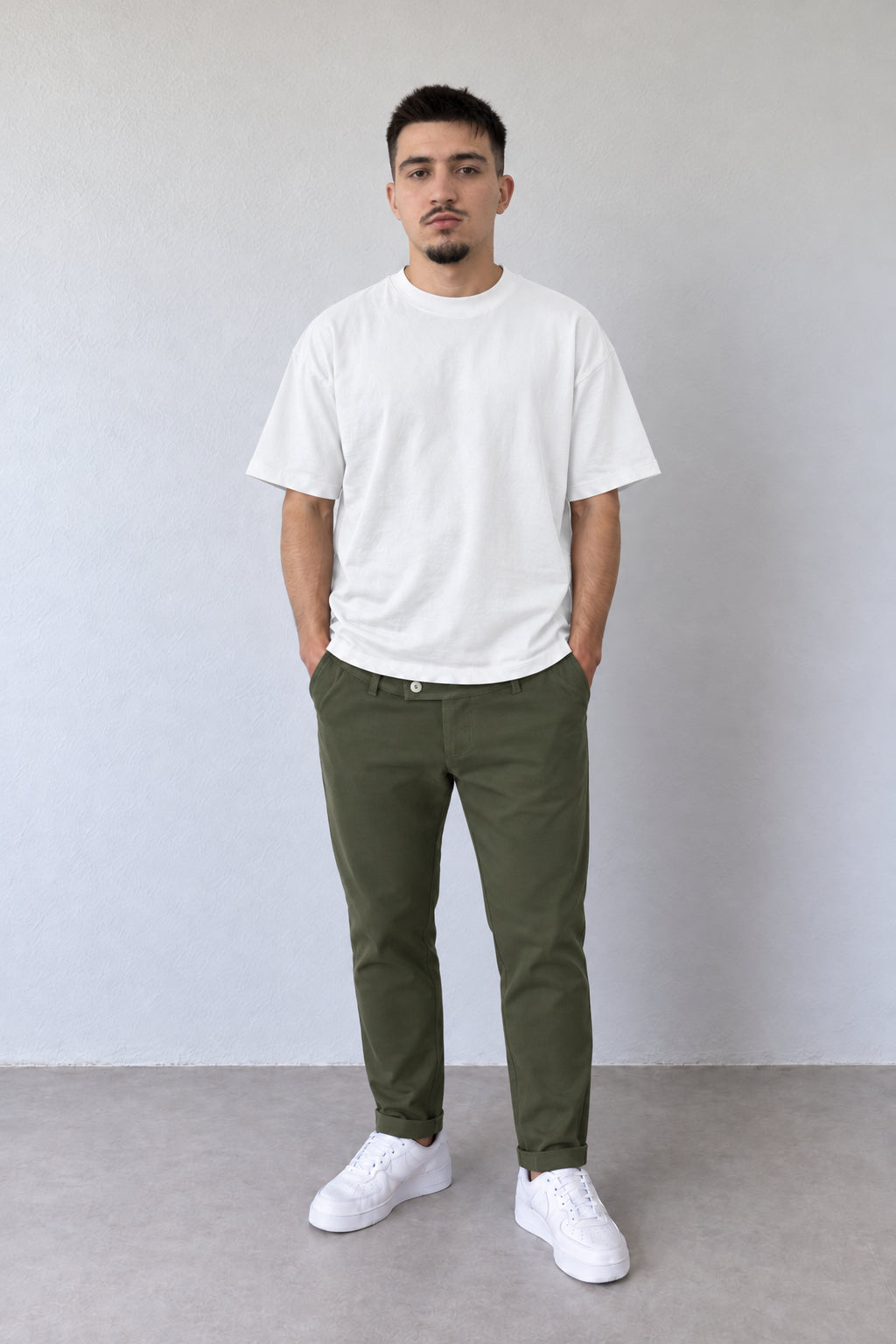 Pantaloni kaki slim pentru bărbați, cu găici pentru curea și rever la glezne, într-o ținută cu tricou alb.