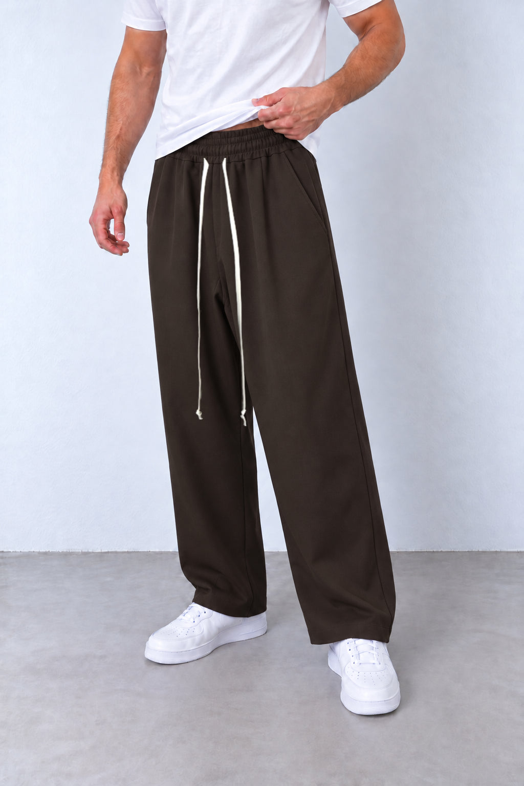 Pantaloni maro pe model, vedere din trei sferturi cu talie elastică și șnur alb lung.