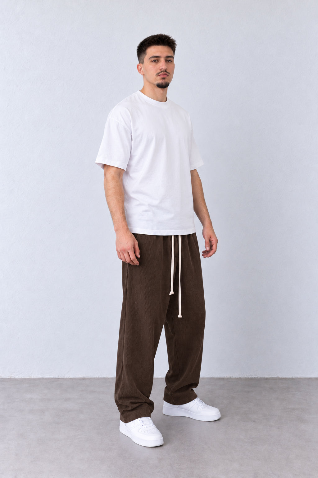 Pantaloni Bărbați Maro Raiați Largi cu Șnur Lung, vedere pe model cu poziție alternativă a brațelor și picioarelor.