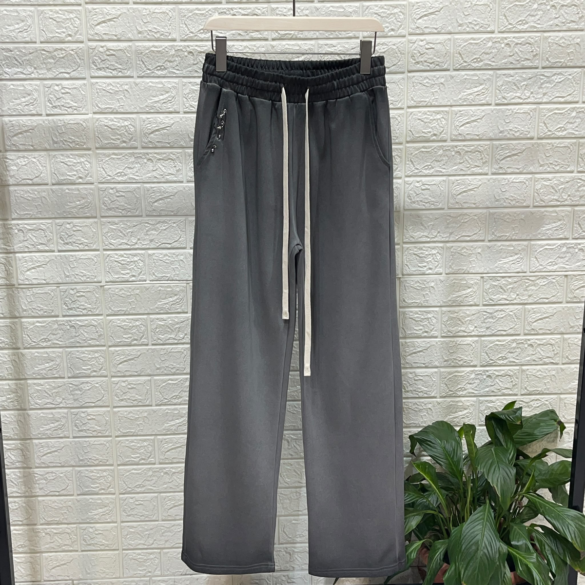 Fotografie reală a pantalonilor negri cu gradient, talie neagră elastică, șnururi lungi ivoire și accesorii metalice mici la buzunar