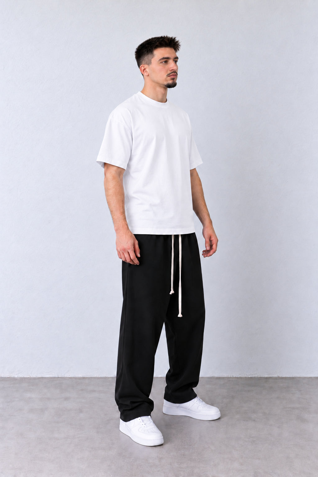 Pantaloni Bărbați Negri Largi cu Șnur Lung, vedere integrală pe model cu capul ușor întors sau înclinat.