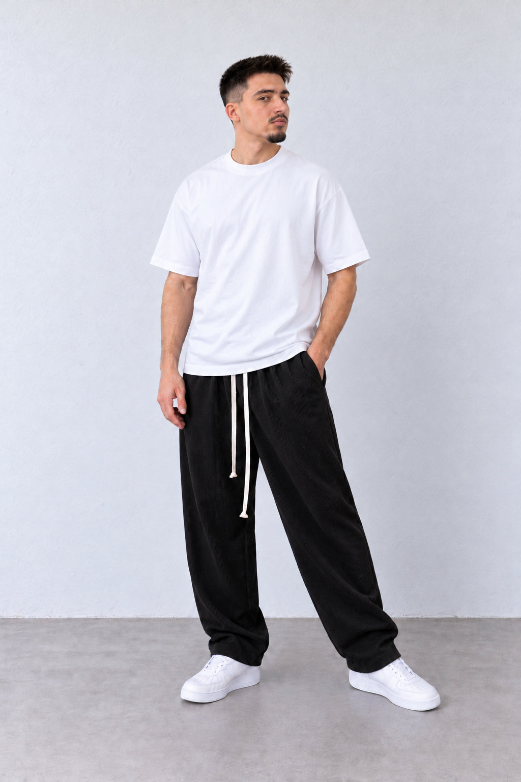 Pantaloni Bărbați Negri Raiați Largi cu Șnur Lung, vedere pe model cu poziție alternativă a brațelor și picioarelor.