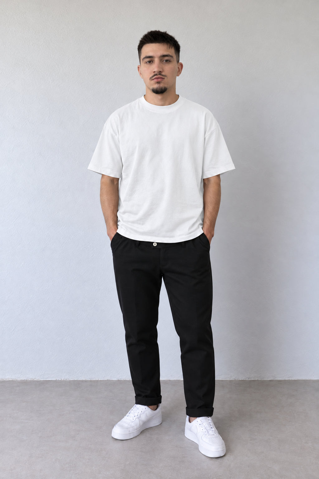 Pantaloni negri slim fit pentru bărbați, cu talie clasică și crac îngustat cu rever, vedere integrală pe model.