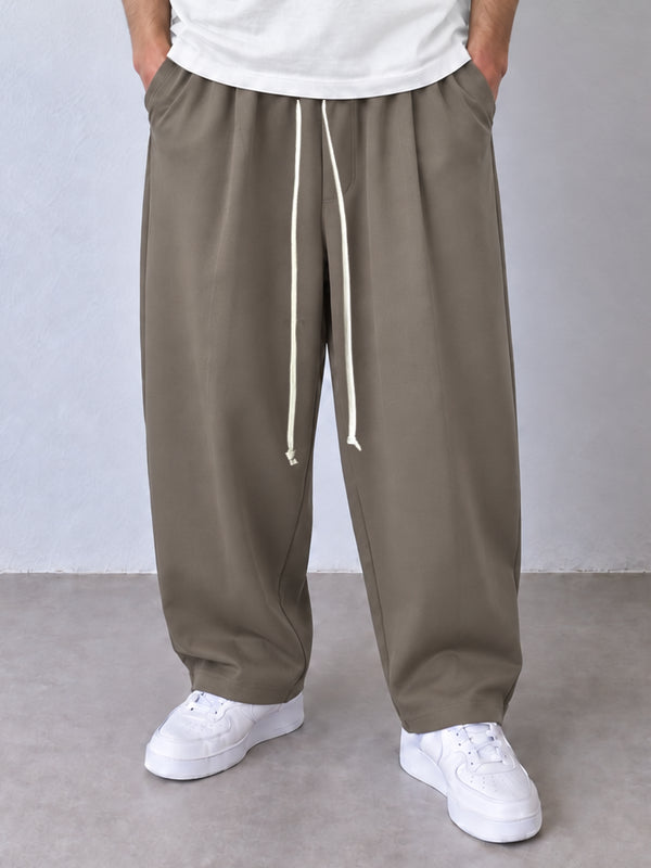 Pantaloni taupe, cadru frontal apropiat cu șnur lung și terminații simple la glezne.
