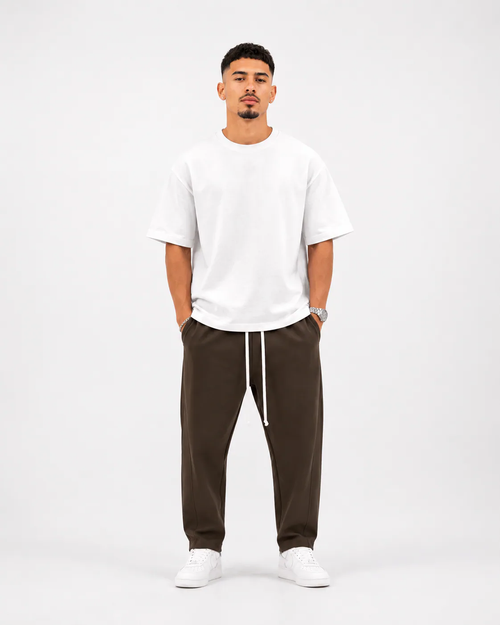 Ședință foto studio pentru pantaloni maro premium streetwear asortați cu tricou alb oversized și pantofi sport albi, stil mod