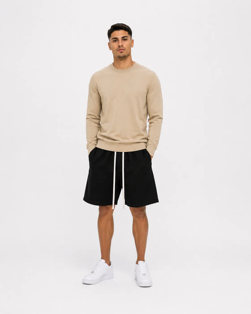 Model masculin purtând bluză bej slim fit premium și pantaloni scurți negri minimalist