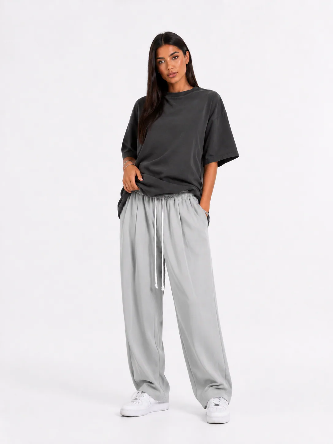 Model feminin cu pantaloni gri cu șnur lung și croială lejeră pentru outfituri trendy.