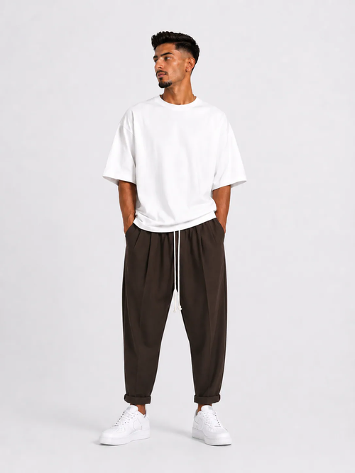 Bărbat purtând pantaloni maro slim cu șiret lung într-un outfit streetwear modern și relaxat.