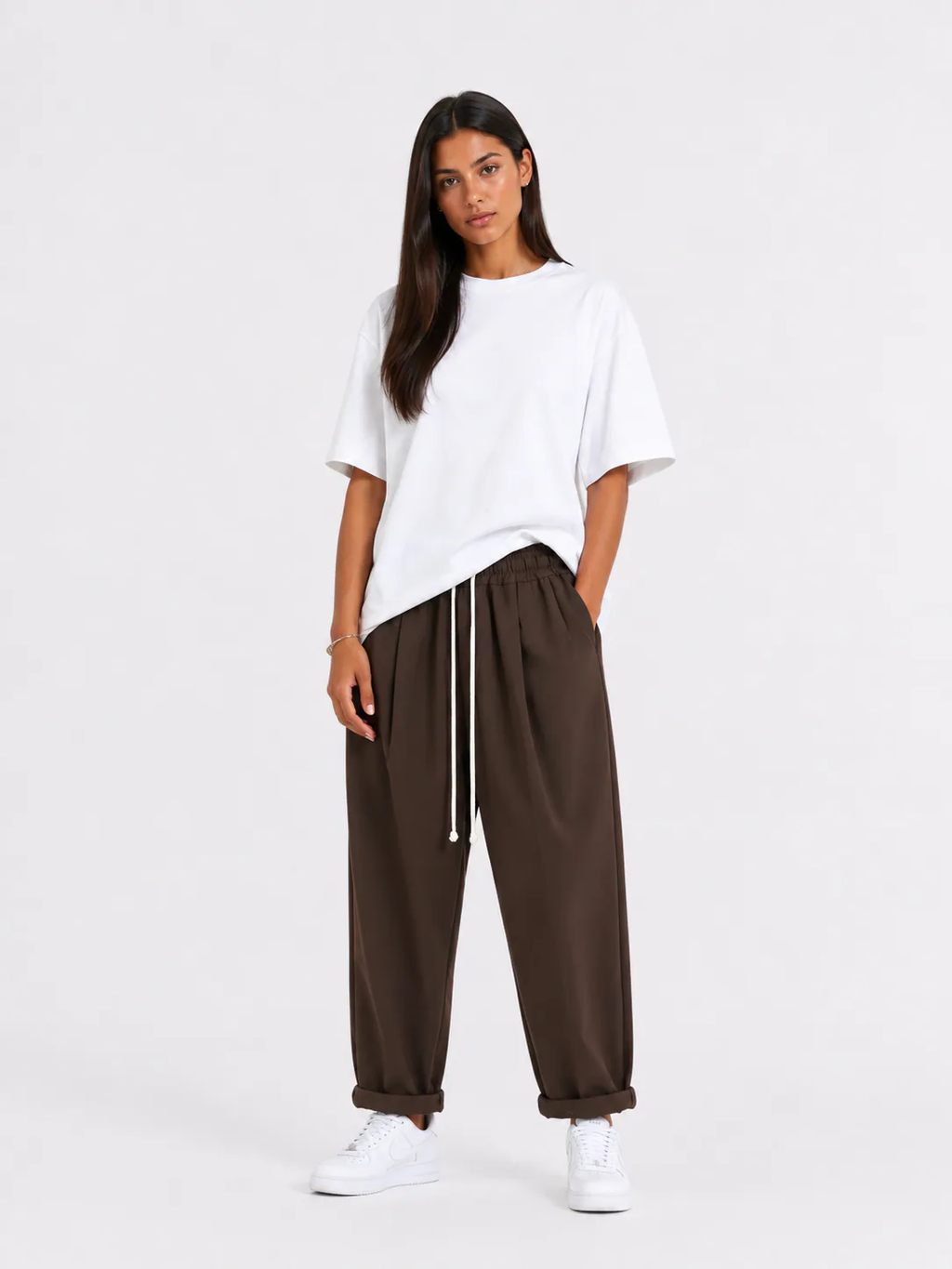 Femeie purtând pantaloni maro cu șiret lung într-un look casual modern și confortabil.