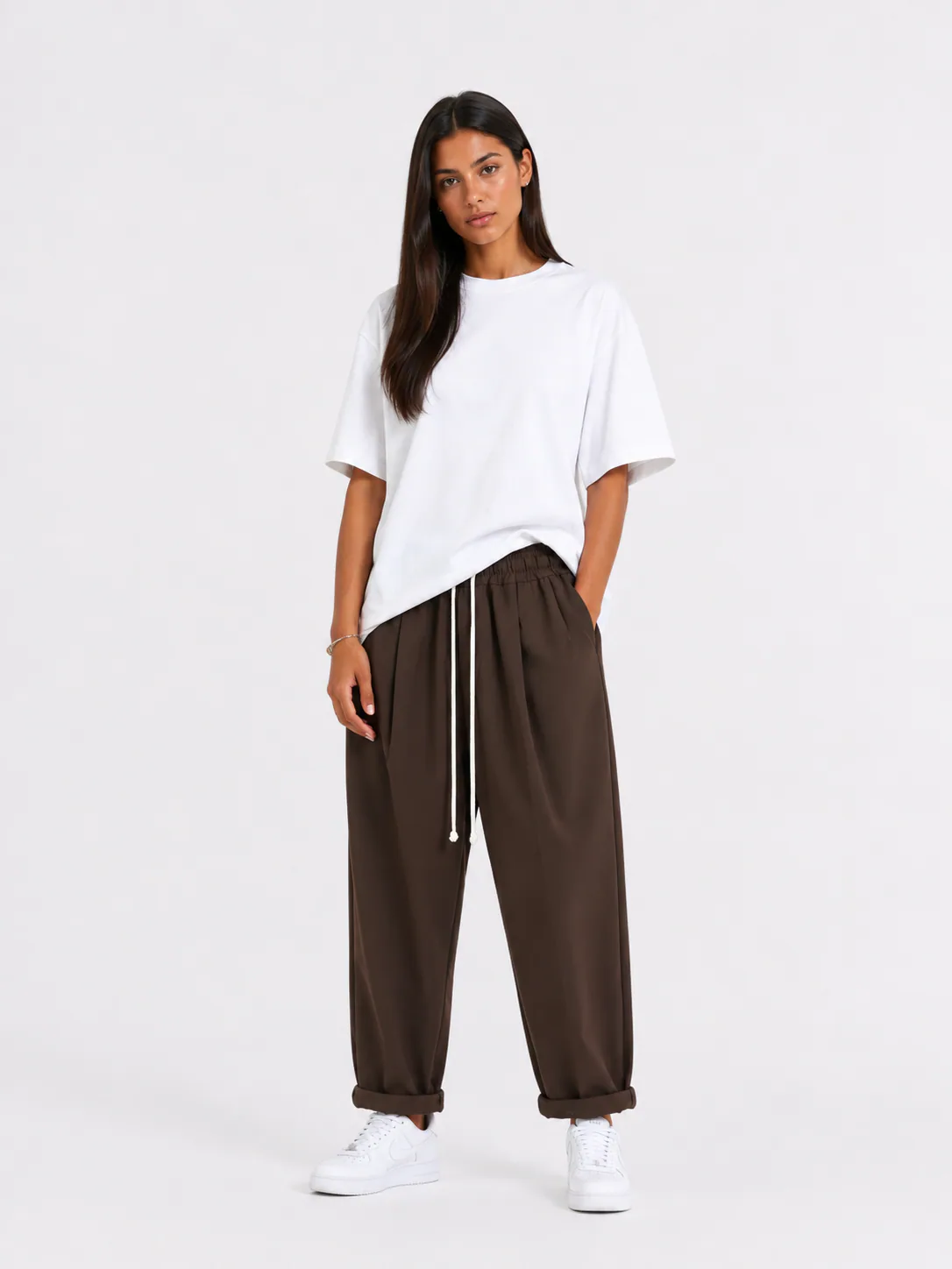 Femeie purtând pantaloni maro cu șiret lung într-un look casual modern și confortabil.