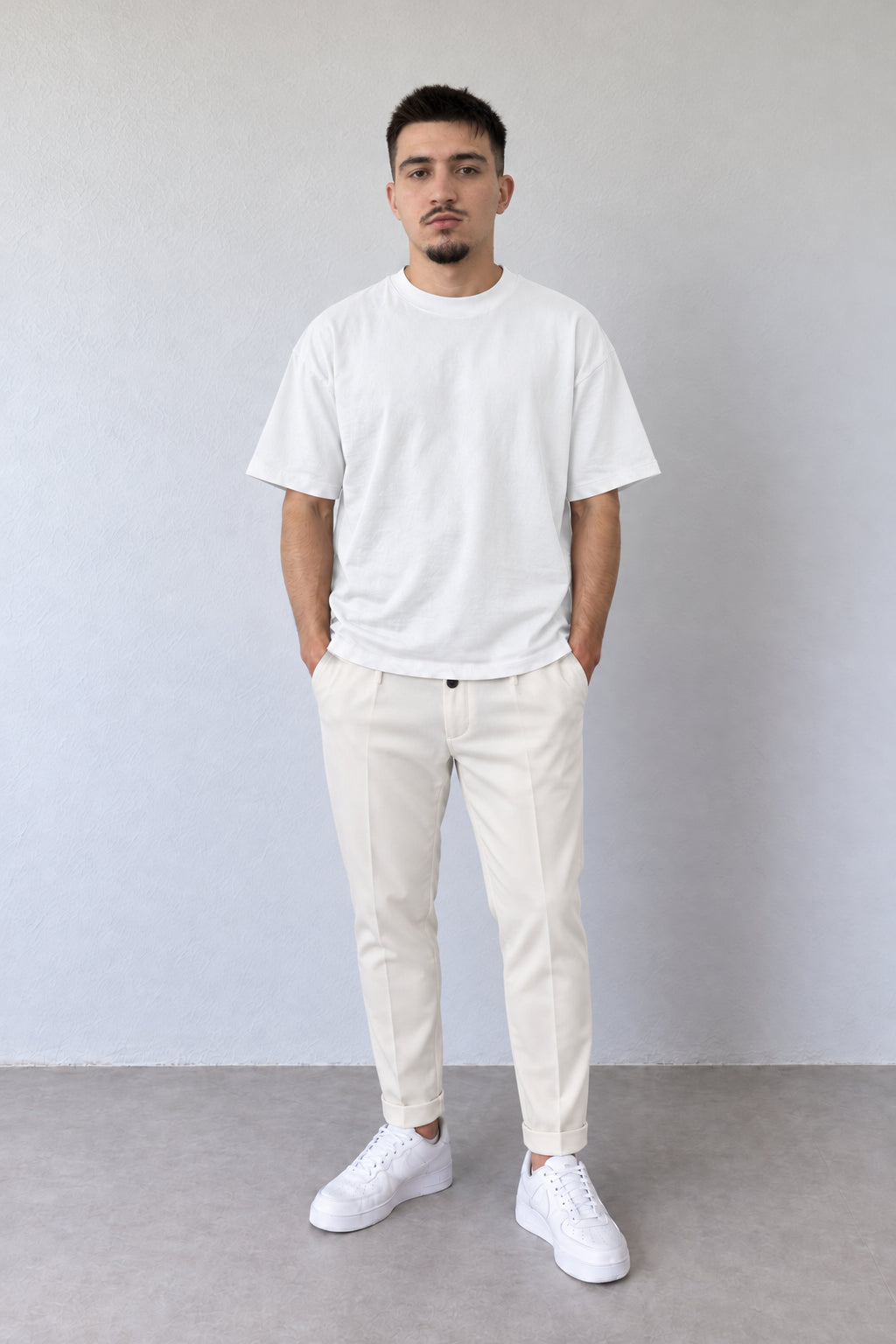 Pantaloni eleganți crem-piersică ALLEN295 pentru bărbați, cu croială slim, nasture închis și tiv întors, purtați cu tricou alb.