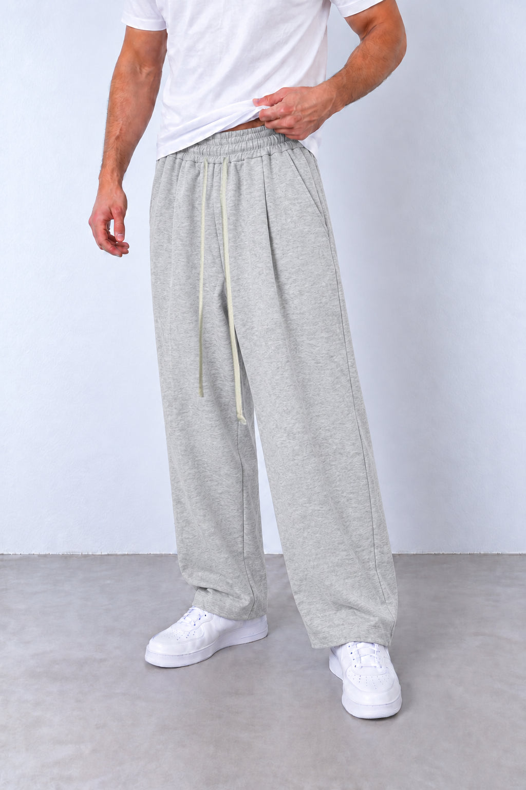 Pantaloni gri-melanj LEO26 pe model, vedere din trei sferturi cu talie elastică, șnur lung și tivuri simple.
