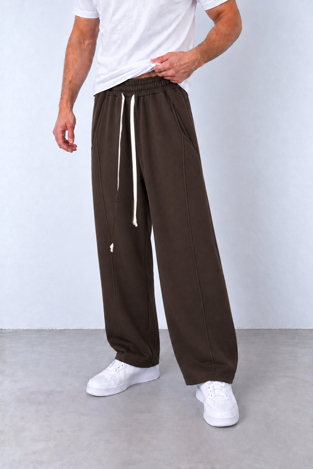 Pantaloni maro LEO26 pe model, vedere din trei sferturi cu talie elastică, șnur lung și tivuri simple.