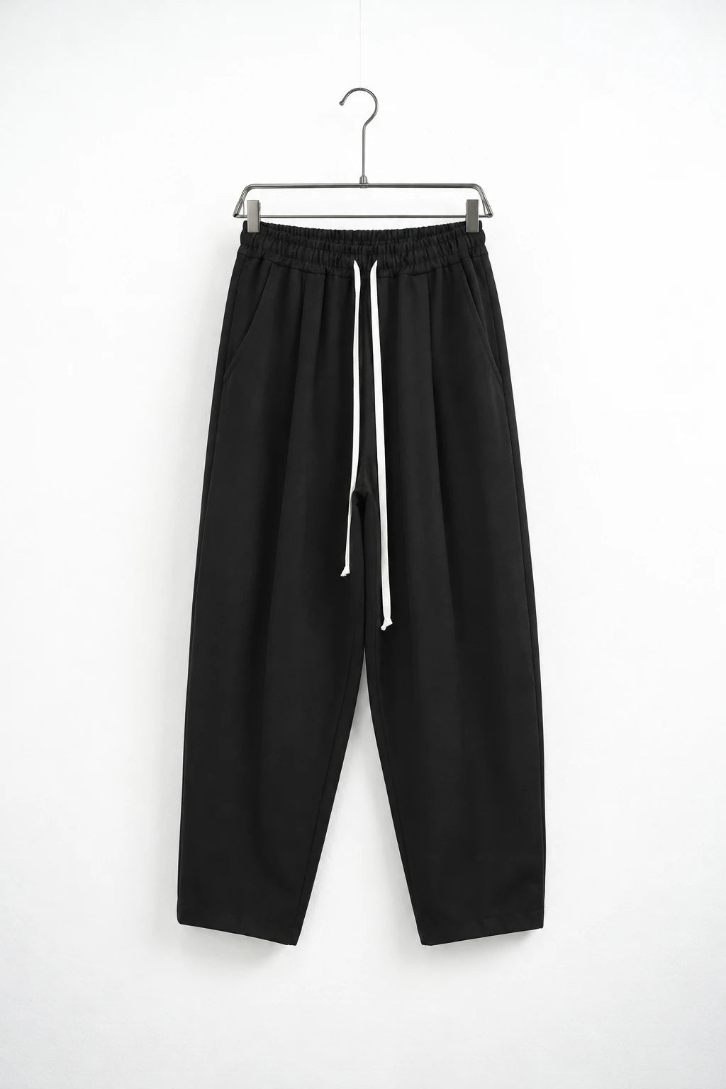 Pantaloni lungi negri carrot fit pentru bărbați, cu talie elastică și șnur alb lung, vedere frontală pe umeraș metalic cu cleme.