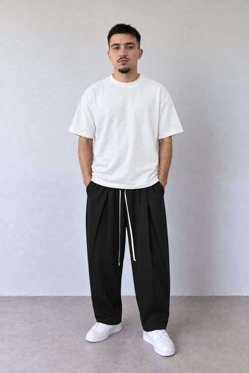 Pantaloni negri pentru bărbați DU-019106 cu pense și șnur lung, purtați cu tricou alb, vedere integrală.