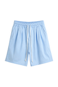 Pantaloni scurți bleu deschis, cu talie elastică și șiret lung alb, prezentați pe un umeraș.