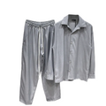 ărbat purtând un set casual gri compus din cămașă și pantaloni lungi cu șnur în talie, dintr-un material ușor elastic.