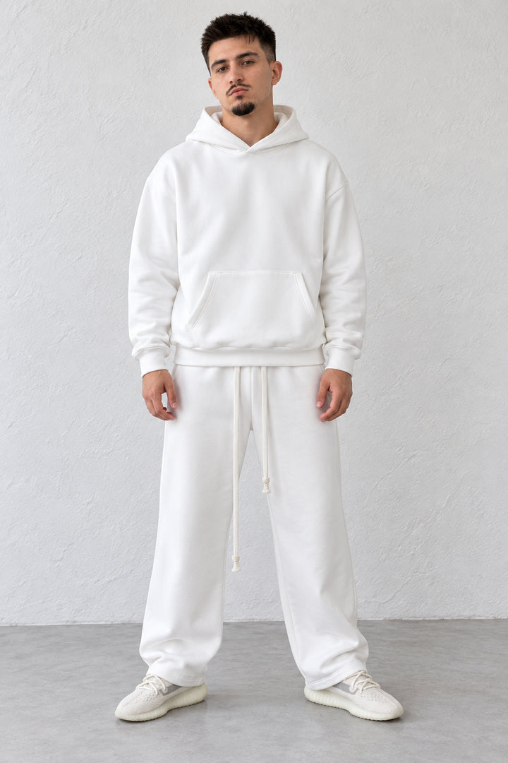 Trening alb pe model, cu hanorac fără șnur la glugă și pantaloni drepți cu șnururi lungi.