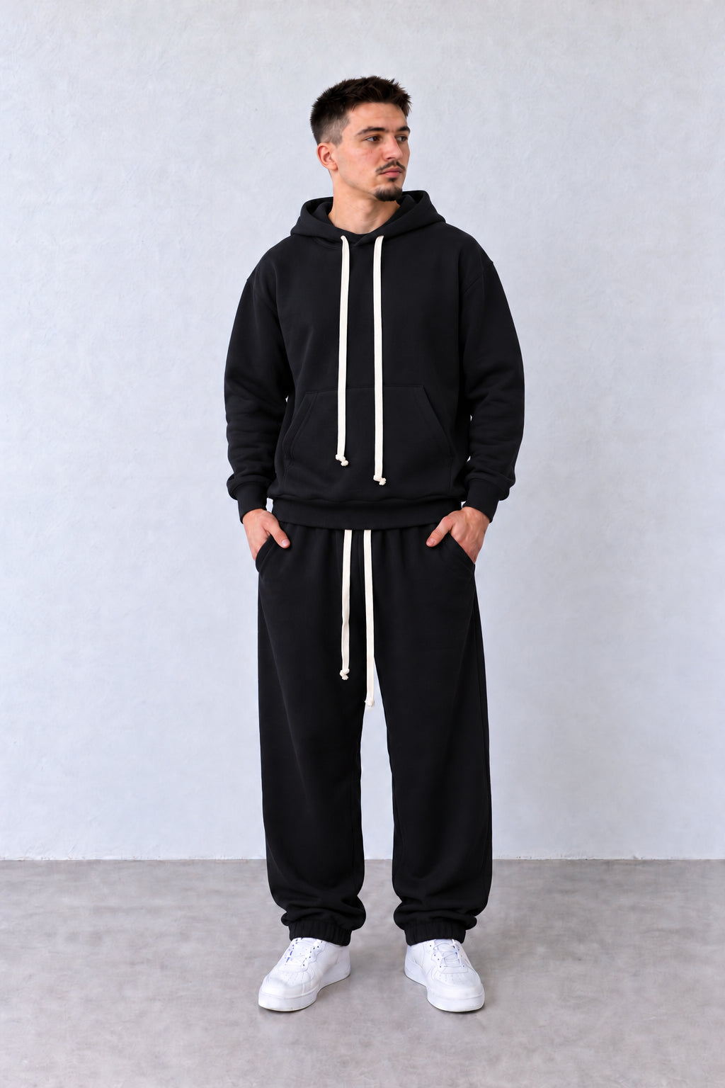 Trening Bărbați Negru cu Glugă și Pantaloni Jogger, vedere integrală pe model cu capul ușor întors sau înclinat.