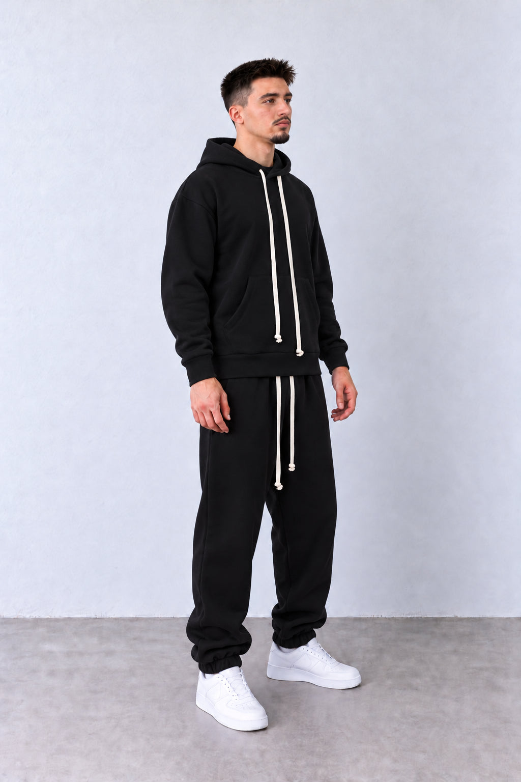 Trening Bărbați Negru cu Glugă și Pantaloni Jogger, vedere pe model cu poziție alternativă a brațelor și picioarelor.