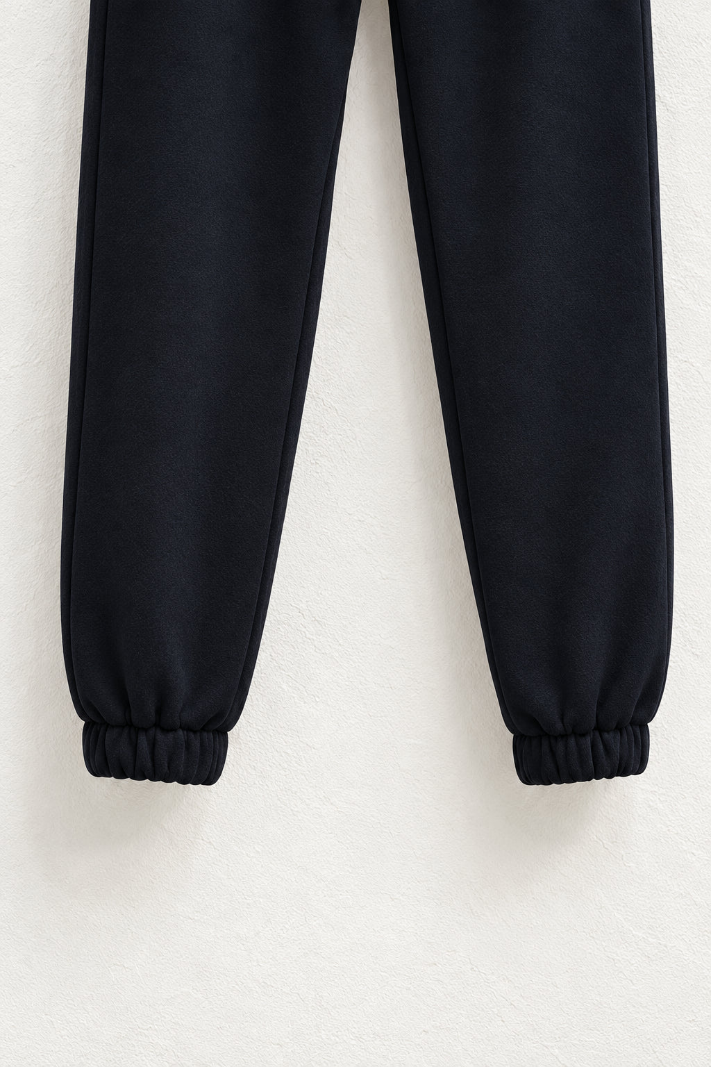 Detaliu al gleznelor elastice și cusăturilor pantalonilor jogger negri