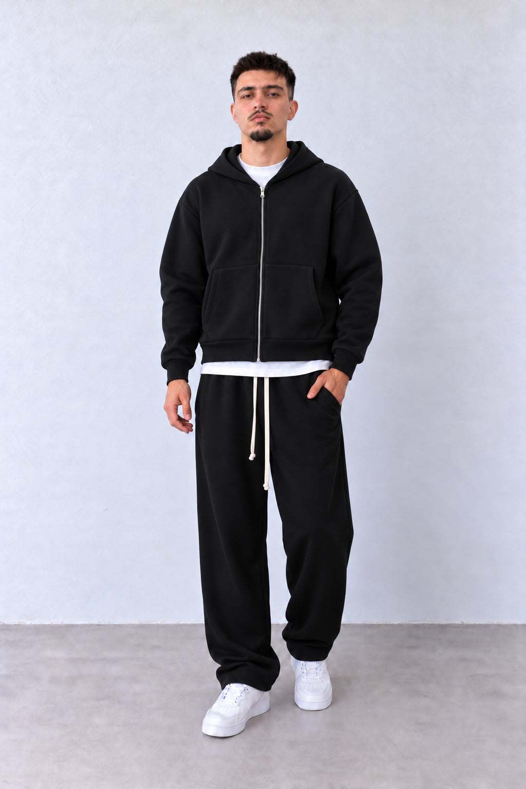 Trening Bărbați Negru Scuba cu Fermoar și Pantaloni Largi, vedere pe model cu poziție alternativă a brațelor și picioarelor.
