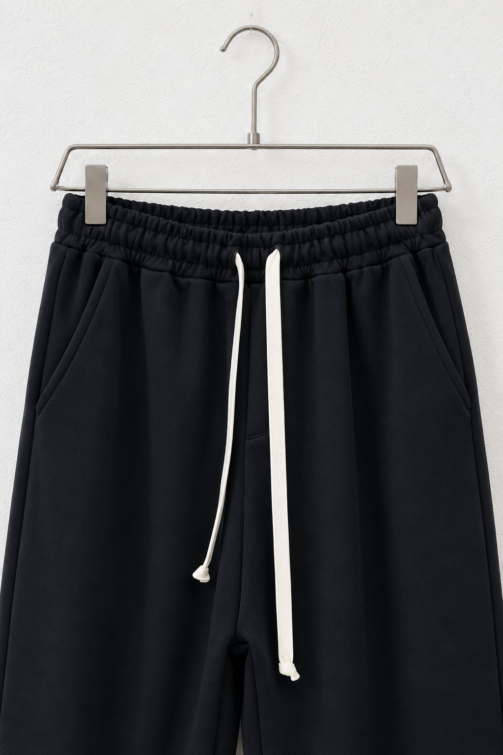 Detaliu al taliei elastice, buzunarelor și șnurului pantalonilor negri scuba