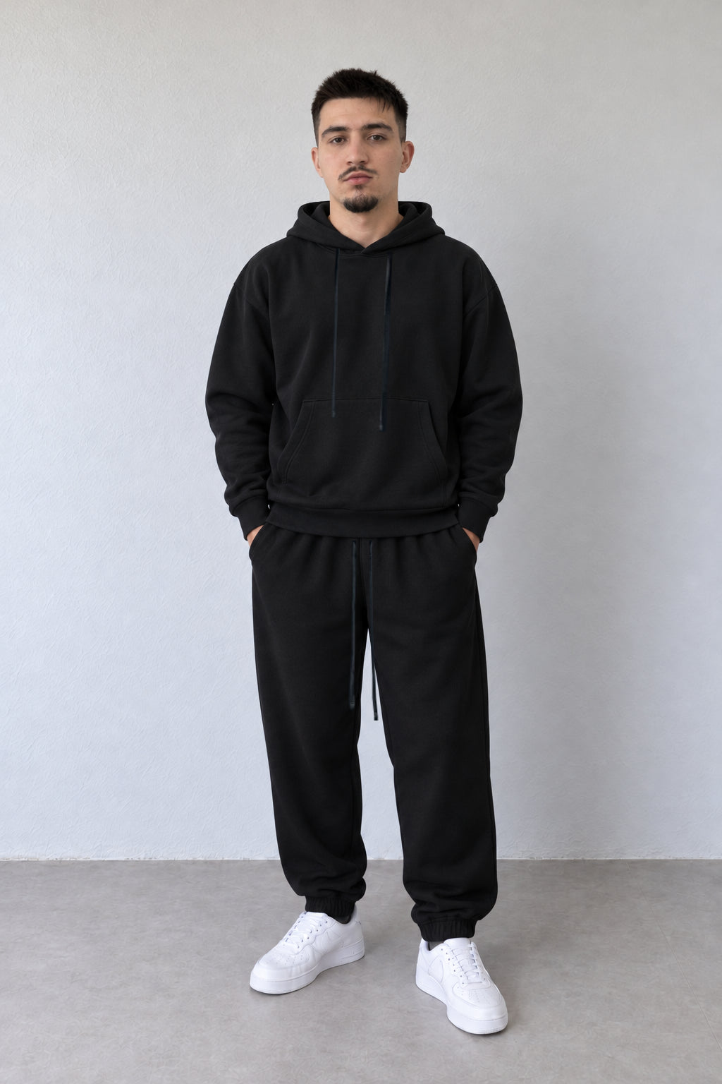 Trening negru bărbătesc 25600, hanorac cu buzunar marsupiu și pantaloni jogger pe model