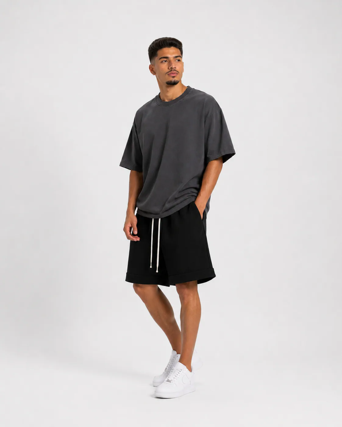 Model masculin purtând tricou gri cu rupturi și outfit minimalist streetwear