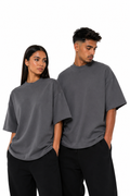 Model femeie și model bărbat purtând tricoul gri închis unisex oversize cu guler strâns Atelier AXD, fotografiat pe fundal alb.