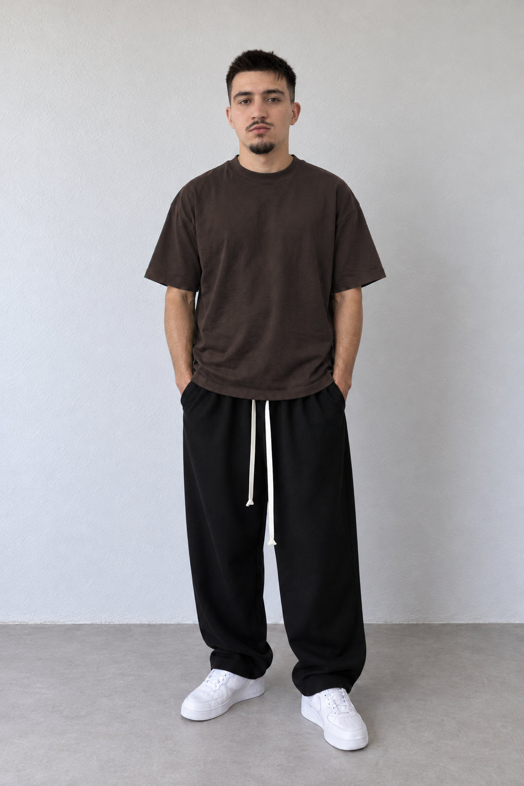 Tricou maro închis L815002 pentru bărbați, cu linie lejeră și mâneci scurte, purtat cu pantaloni negri.