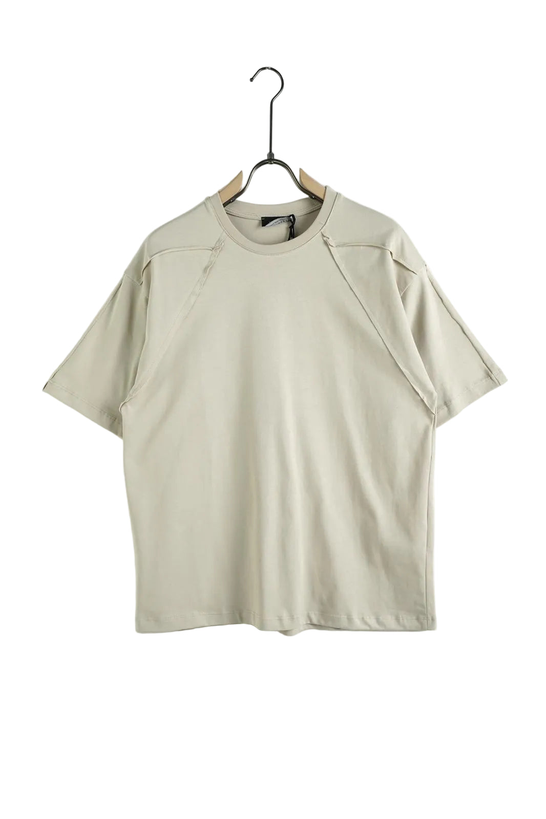 Model purtând un tricou unisex de culoare crem, realizat din 100% bumbac, cu o croială lejeră și un design minimalist accentuat de cusături decorative aparente.