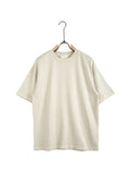 Model purtând un tricou unisex de culoare apricot (piersică deschis), cu o croială lejeră și un design streetwear evidențiat prin detalii de uzură și rupturi decorative.